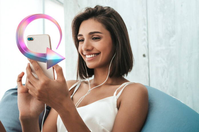 refresh-camera-prive Mulher sorrindo enquanto usa o smartphone, representando a dica de atualizar a página para voltar ao topo no Camera Prive.