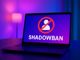 Notebook moderno em uma sala com iluminação roxa e azul, exibindo um alerta de shadowban na tela, representando o impacto das restrições em conteúdo sensual nas redes sociais.