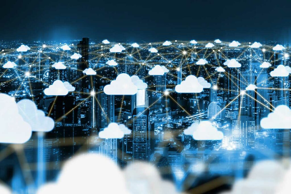 Cidade iluminada à noite conectada por ícones de nuvem digital, representando rede global de computação em nuvem e compartilhamento de dados online