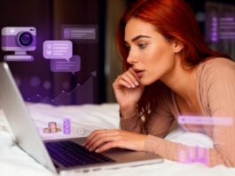 Como ganhar dinheiro sendo modelo de webcam: guia completo Mulher ruiva usando notebook na cama com ícones roxos de webcam, chat, moedas e gráfico de crescimento.