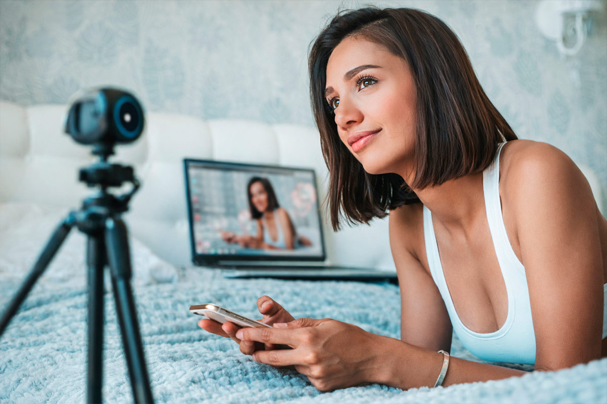 Mulher trabalhando com transmissões ao vivo pelo celular e webcam, representando como ganhar dinheiro como camgirl online